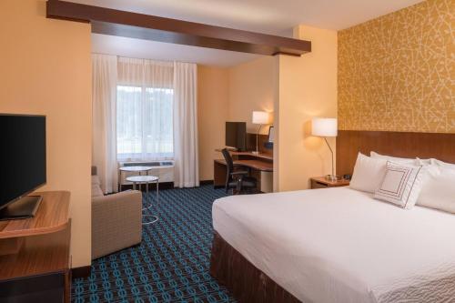 a hotel room with a bed and a television at Fairfield By Marriott Huntington in Huntington