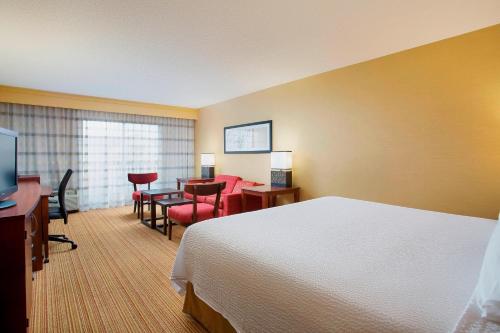 um quarto de hotel com uma cama, uma mesa e cadeiras em Courtyard Chicago Midway Airport em Bedford Park