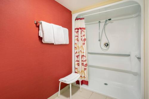 a bathroom with a shower and a white chair at Courtyard Chicago Midway Airport in Bedford Park
