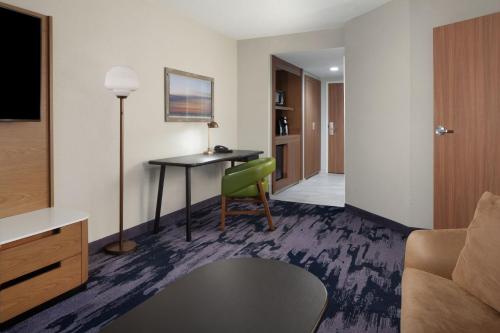 a living room with a table and a green chair at Fairfield Inn & Suites by Marriott Charleston in Charleston