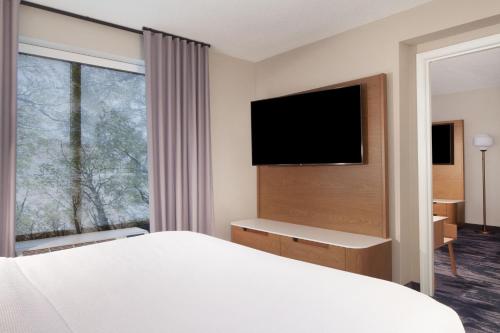 a hotel room with a bed and a flat screen tv at Fairfield Inn & Suites by Marriott Charleston in Charleston