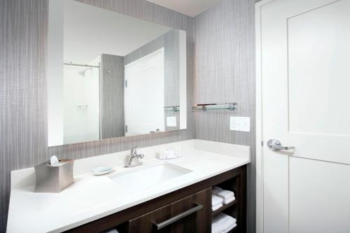Residence Inn by Marriott Baltimore Owings Mills في أوينغز ميلز: حمام مع حوض أبيض ومرآة