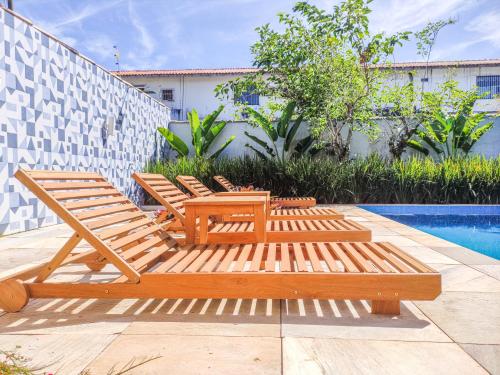 a group of wooden lounge chairs next to a pool at Casa Azul Hibisco - Geriba Buzios in Búzios