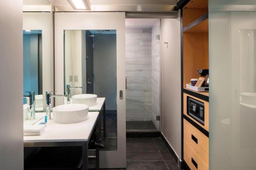 a bathroom with two sinks and two mirrors at Aloft Coral Gables in Miami