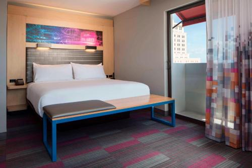 a bedroom with a bed and a desk and a window at Aloft Coral Gables in Miami