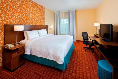 Habitación de hotel con cama, escritorio y TV. en Fairfield Inn & Suites Houston Hobby Airport, en Houston