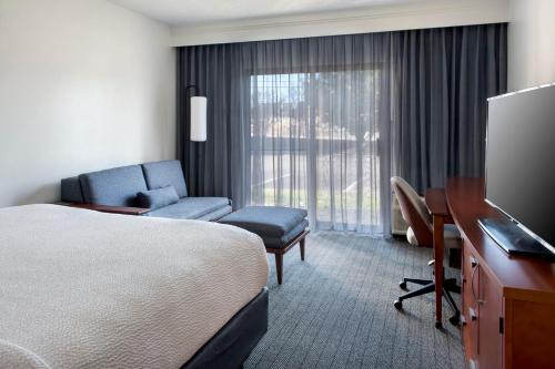 Habitación de hotel con cama, escritorio y TV. en Courtyard by Marriott Annapolis en Annapolis