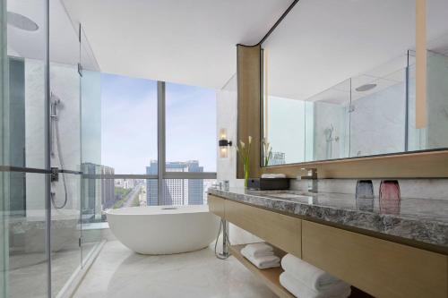 La salle de bains est pourvue d'une baignoire et d'un grand miroir. dans l'établissement Baotou Marriott Hotel, à Baotou