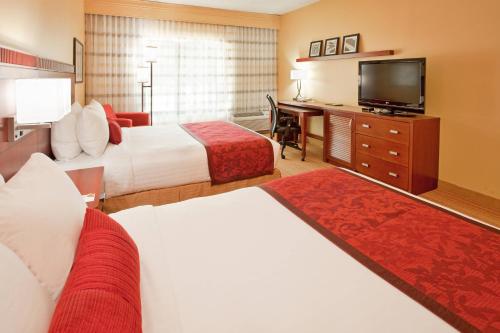 a hotel room with two beds and a flat screen tv at Courtyard Houston The Woodlands in The Woodlands