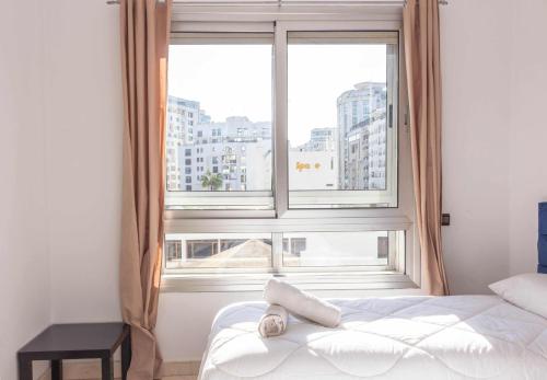 a bed in a room with a large window at Appartement Haut Standing Central Corniche in Tangier