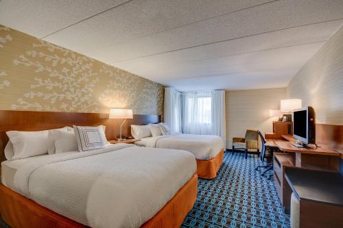 a hotel room with two beds and a television at Fairfield Inn Boston Woburn in Woburn