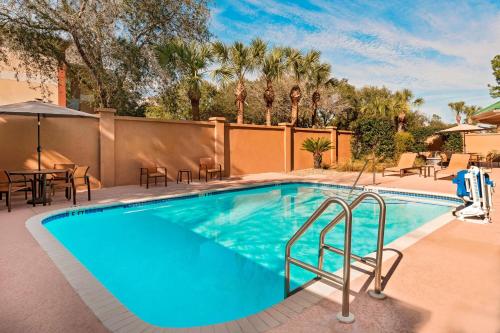 una piscina con mesas y sillas en un complejo en Courtyard by Marriott Gainesville FL, en Gainesville