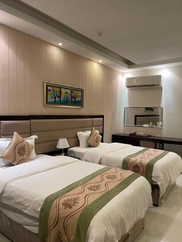 una camera d'albergo con due letti e uno specchio di فندق مرسى جيزان a Jazan