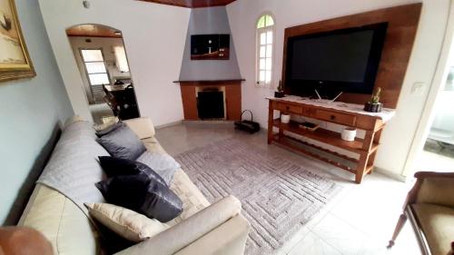 sala de estar con sofá y TV de pantalla plana en Casa Campos do Jordão, en Campos do Jordão