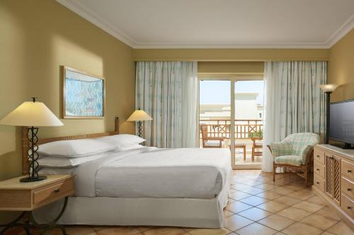 1 dormitorio con cama, TV y balcón en Sheraton Soma Bay Resort, en Hurghada