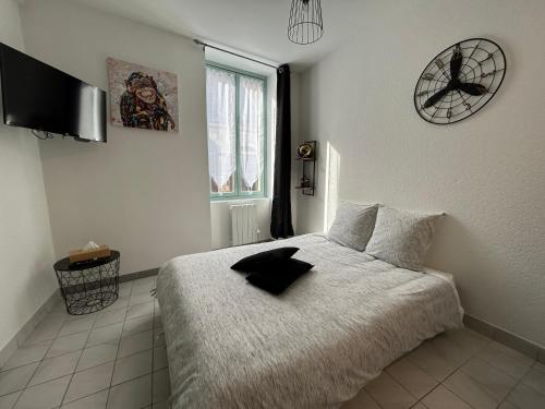 een slaapkamer met een bed en een klok aan de muur bij Au 15 - Charmant Studio hyper centre in Saint-Amand-Montrond