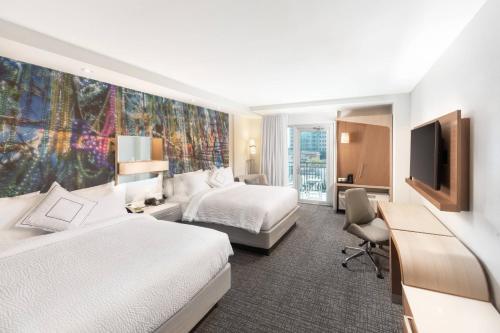 a hotel room with two beds and a flat screen tv at Courtyard by Marriott Baton Rouge Downtown in Baton Rouge