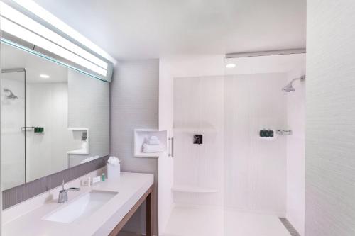 a white bathroom with a sink and a shower at Courtyard by Marriott Baton Rouge Downtown in Baton Rouge