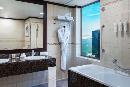 a bathroom with two sinks and a tub and a window at Delta Hotels by Marriott Jumeirah Beach, Dubai in Dubai