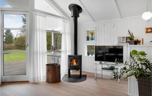 a fireplace in a living room with a tv and a fire at Lovely Home In Dannemare With Sauna in Kramnitse