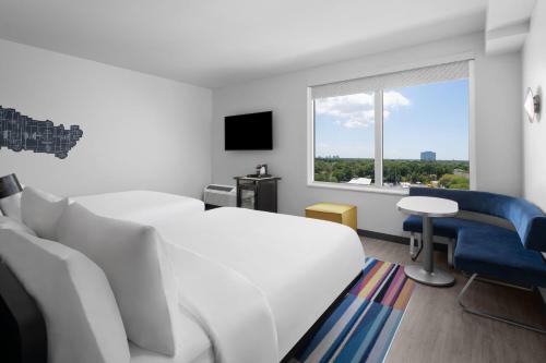 a hotel room with a bed and a chair and a window at Aloft Tampa Midtown in Tampa