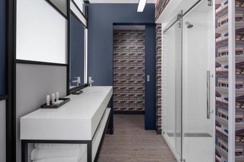 a bathroom with a white vanity and a brick wall at Aloft Tampa Midtown in Tampa