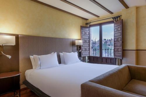 a bedroom with a large white bed and a window at AC Hotel Ciudad de Toledo by Marriott in Toledo