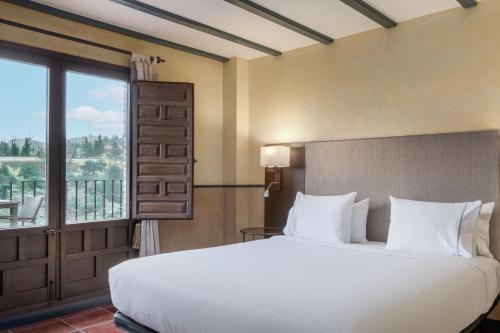 a bedroom with a large bed and a large window at AC Hotel Ciudad de Toledo by Marriott in Toledo