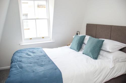 a bedroom with a bed with blue pillows and a window at Margarets Buildings in Bath