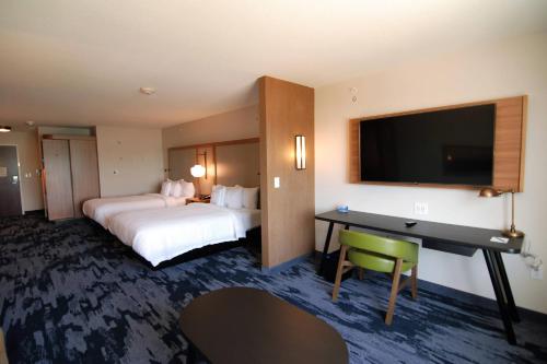 ein Hotelzimmer mit 2 Betten, einem Schreibtisch und einem TV in der Unterkunft Fairfield Inn & Suites Winona in Winona