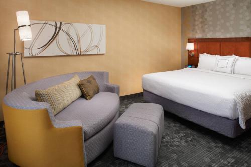 um quarto de hotel com uma cama e uma cadeira em Courtyard by Marriott Detroit Warren em Warren