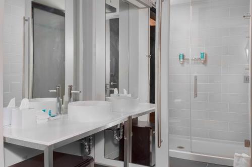 - Baño blanco con 2 lavabos y ducha en Aloft Gainesville University Area, en Gainesville
