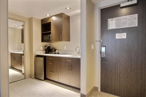 uma cozinha com armários de madeira, um lavatório e uma porta em Courtyard by Marriott Quebec City em Cidade de Quebec