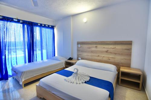 Habitación de hotel con 2 camas y ventana en Hotel Comercial, en Sincelejo