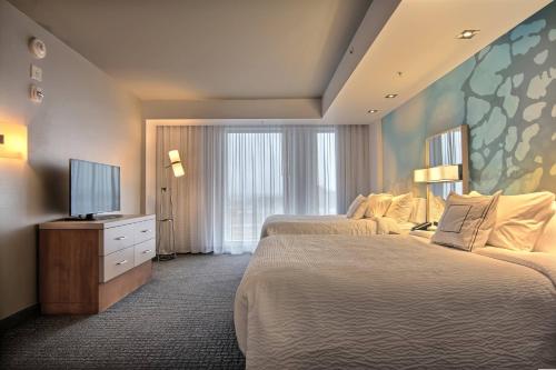 a hotel room with two beds and a flat screen tv at Courtyard by Marriott Quebec City in Quebec City