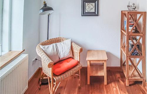 a wicker chair with a red pillow and a table at 2 Bedroom Lovely Home In Tönning in Tönning