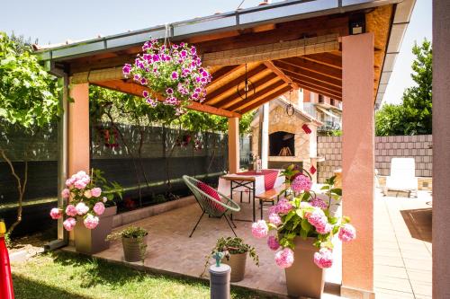 a pergola with flowers in pots on a patio at Apartman Sunny Vacay in Kaštela