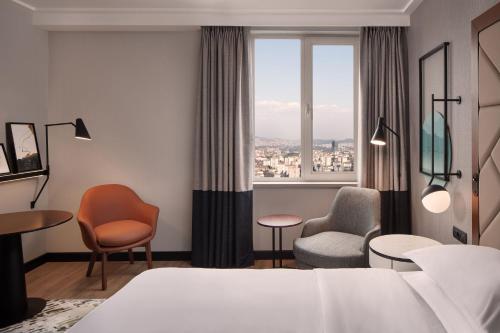 a hotel room with a bed and chairs and a window at Sheraton Istanbul Levent in Istanbul