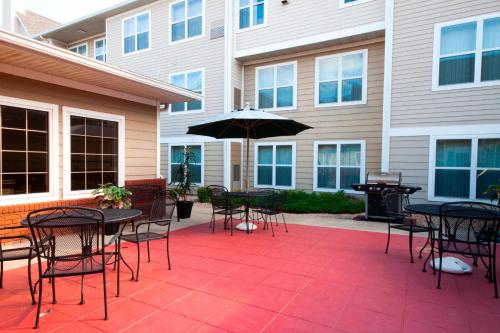 un patio con tavoli, sedie e ombrellone di Residence Inn by Marriott Oklahoma City South a Oklahoma City