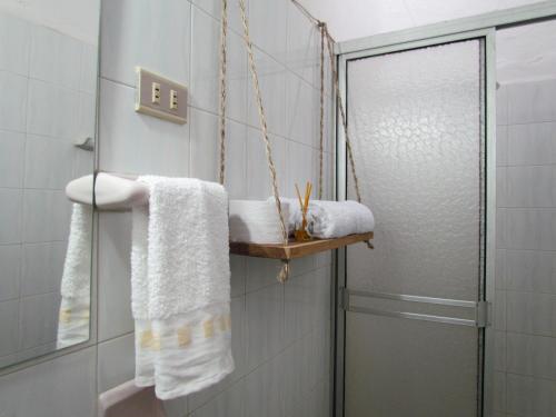 a bathroom with a shower and towels on a shelf at Casa Yerbabuena- Rustiko in Barichara