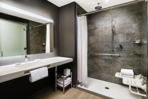 a bathroom with a sink and a shower at AC Hotel By Marriott Raleigh Downtown in Raleigh