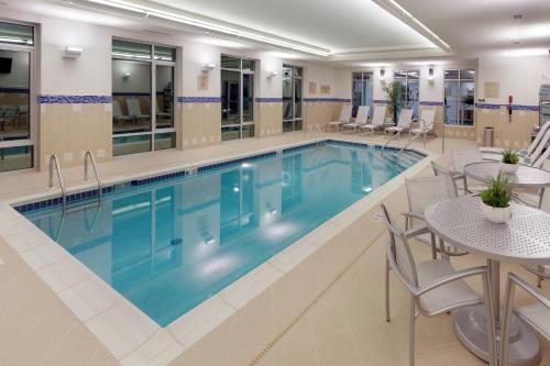 einen Pool in einem Hotel mit Tischen und Stühlen in der Unterkunft TownePlace Suites by Marriott Springfield in Springfield