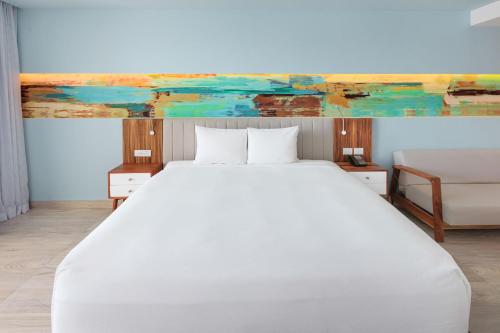 a bedroom with a white bed and a painting on the wall at Courtyard by Marriott Mazatlan Beach Resort in Mazatlán