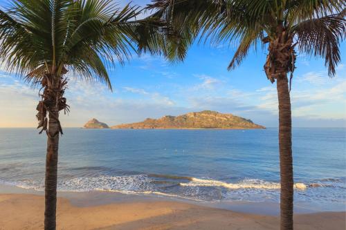 two palm trees on a beach near the ocean at Courtyard by Marriott Mazatlan Beach Resort in Mazatlán