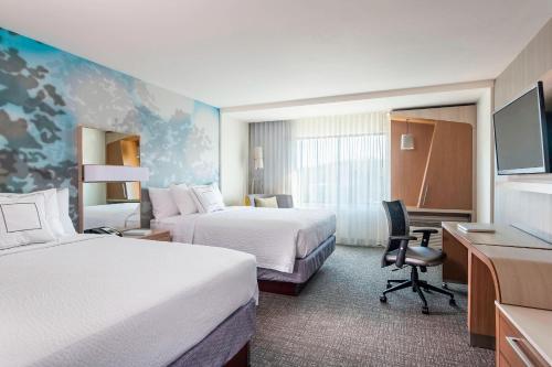 a hotel room with two beds and a desk at Courtyard Sioux City Downtown/Convention Center in Sioux City