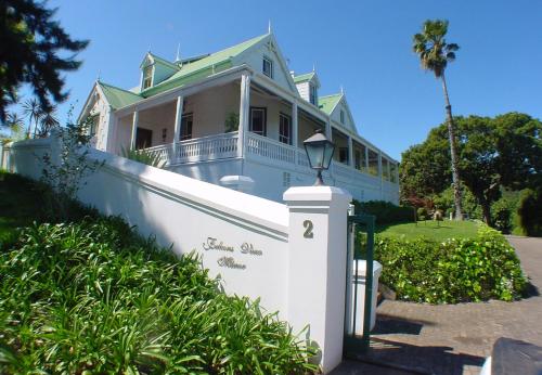 a white house with a green roof and a fence at Falcons View Manor in Knysna