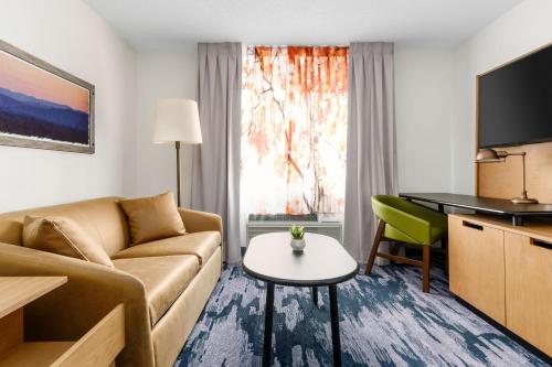 a living room with a couch and a table and a tv at Fairfield Inn by Marriott Joliet South in Joliet