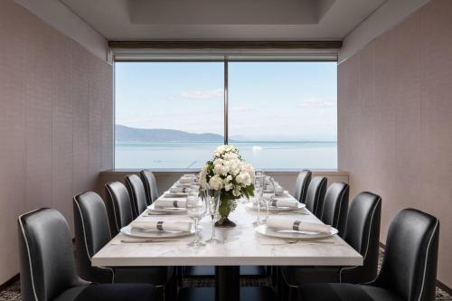 a long table with chairs and a vase of flowers at Lake Biwa Marriott Hotel in Moriyama