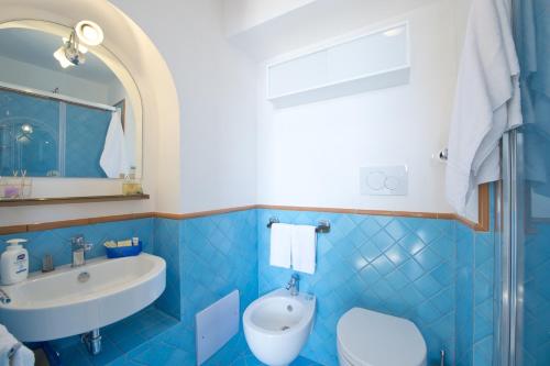 a blue tiled bathroom with a sink and a toilet at La Scivitella in Amalfi