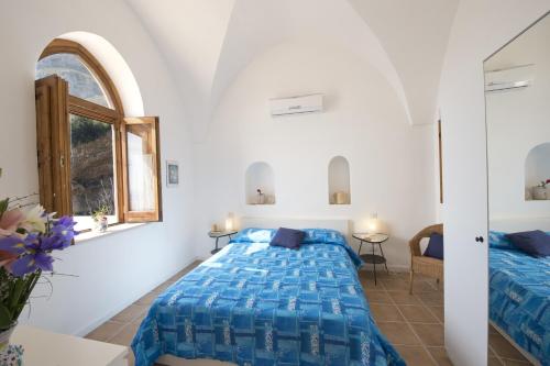 a white bedroom with a bed and a window at La Scivitella in Amalfi